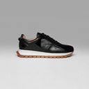 Black leather sneaker with a white sole on a gray background